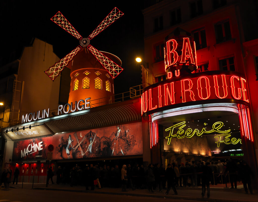 Paris Moulin Rouge Außenansicht mit leuchtenden Schriftzügen und einer Mühle