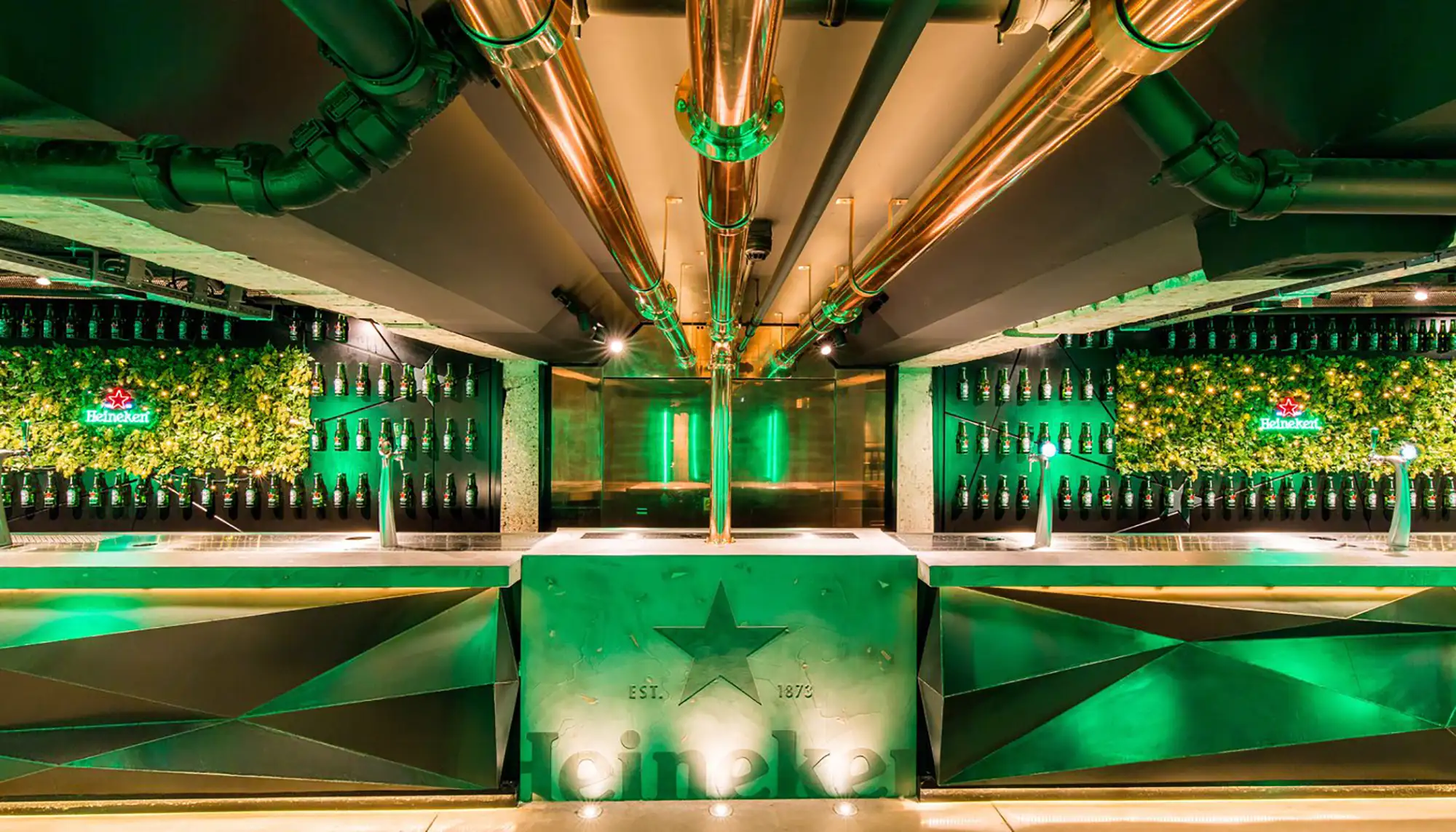 Heineken Experience Amsterdam Theke in der Best Dam Bar mit Zapfsäulen und Flaschen mit grüner Beleuchtung