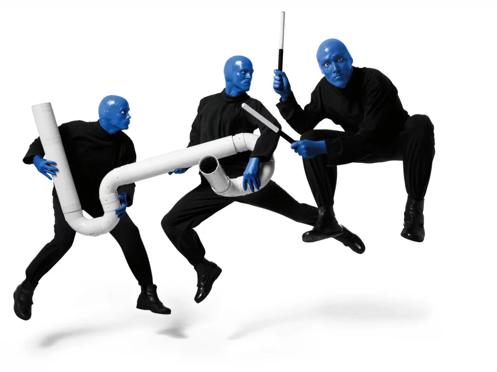 Show Blue Man Group in Berlin - 3 blaue Männer in schwarzer Kleidung springen in die Luft