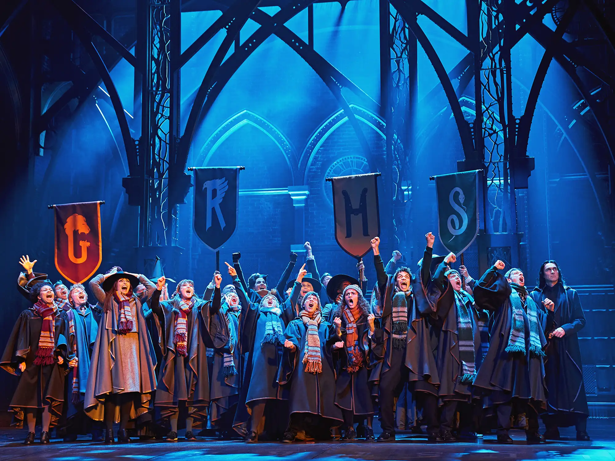 Harry Potter Musical - Schauspieler auf der Bühne mit Zauberstäben und Bannern