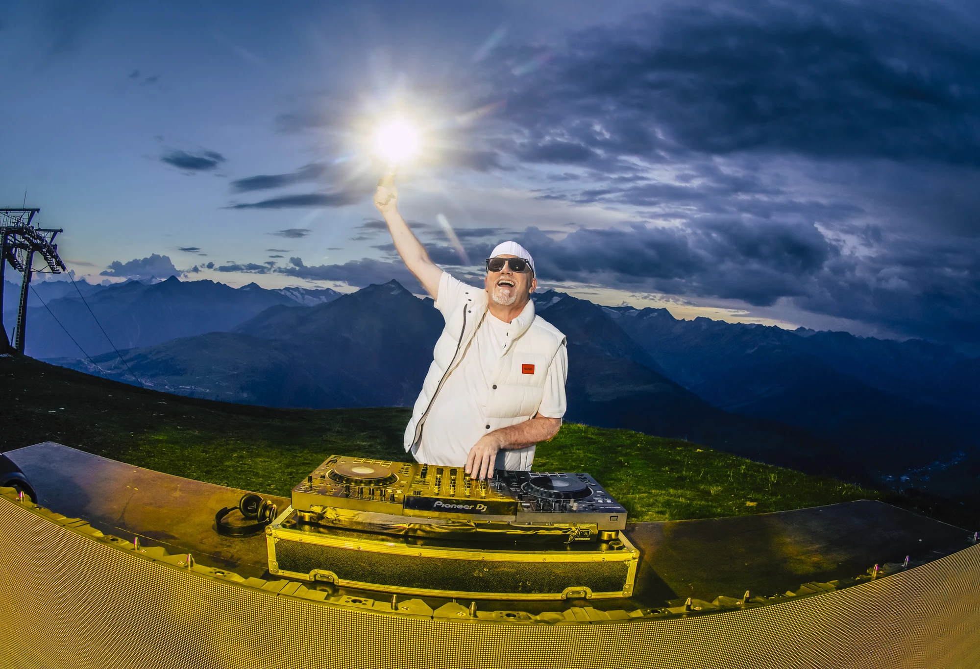 Mountain Mania 2024 - DJ Ötzi Konzert - DJ Ötzi am Mischpult vor Bergkulisse mit Licht in der Hand