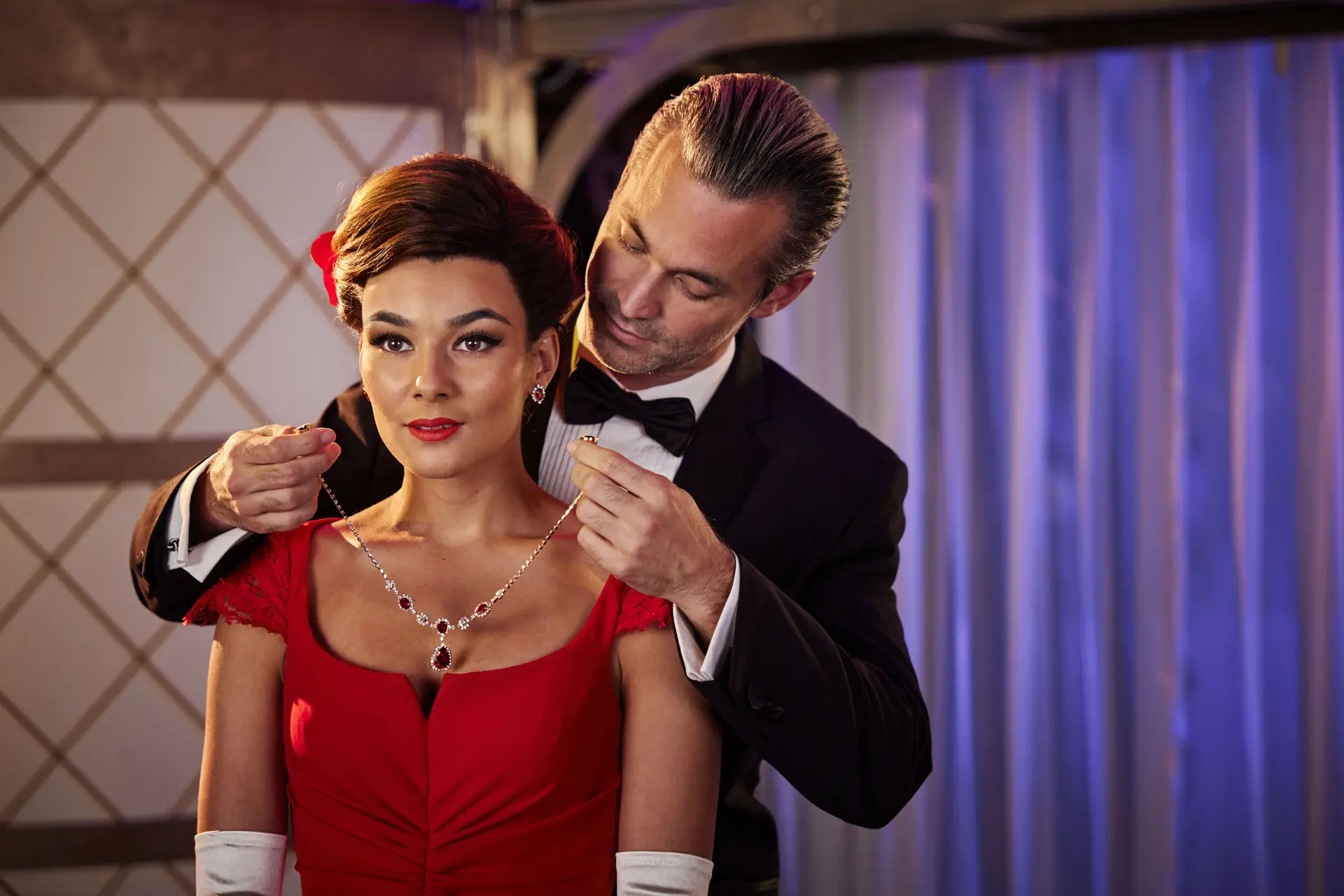 Edward (im Anzug) legt Vivian (im roten Kleid) ein Rubin besetztes Collier um (Szene aus Pretty Woman – Das Musical)